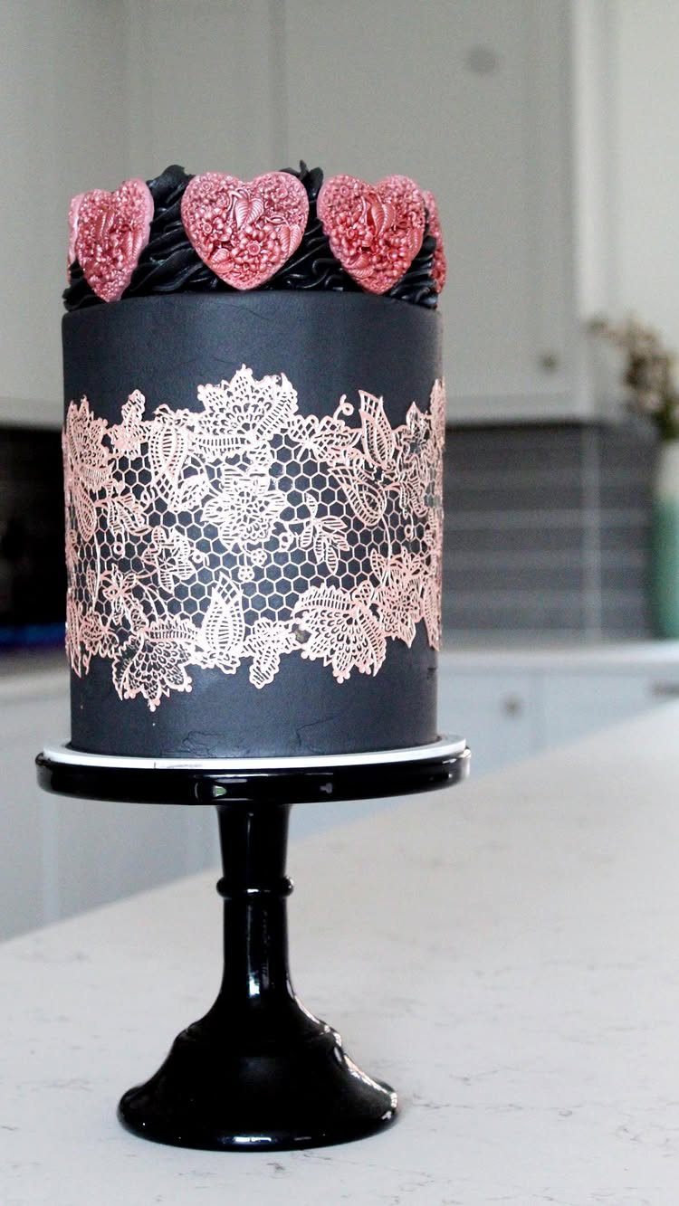 38 Romantic Wedding Cake Ideas for Your Celebration 16 Black single-tier cake with pink lace patterns and heart decorations on a stand