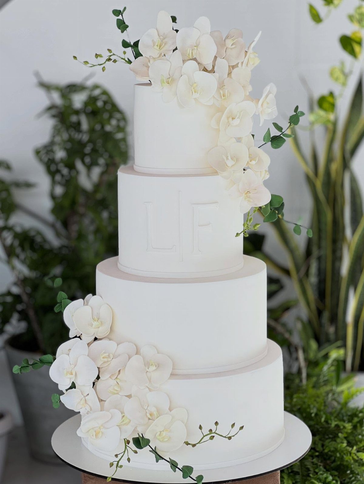 38 Romantic Wedding Cake Ideas for Your Celebration 31 Four-tier white wedding cake adorned with elegant white orchids and green foliage.