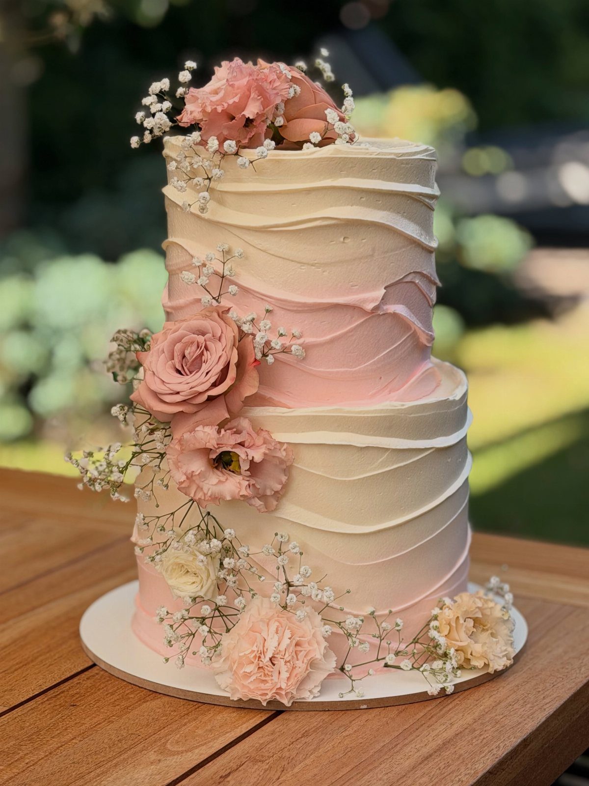 38 Romantic Wedding Cake Ideas for Your Celebration 6 Two-tier pink and white swirled wedding cake decorated with fresh pink roses and baby's breath.