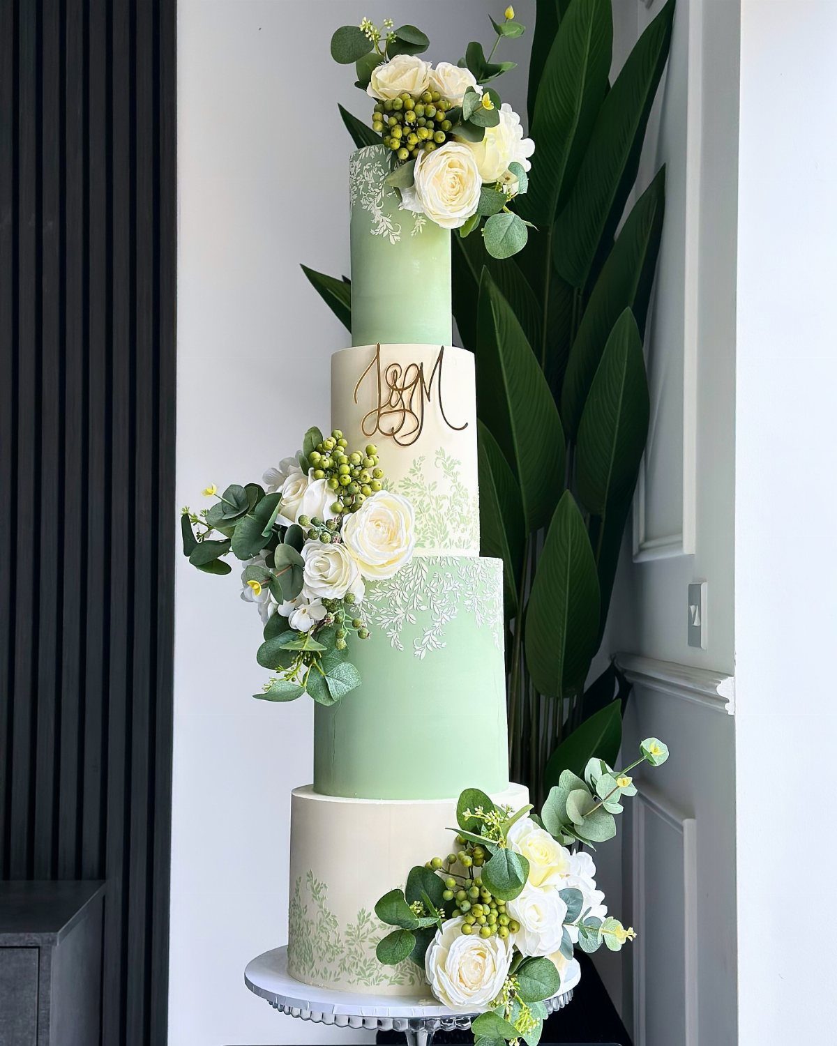 38 Romantic Wedding Cake Ideas for Your Celebration 27 Four-tier wedding cake with sage green and cream layers decorated with white roses.