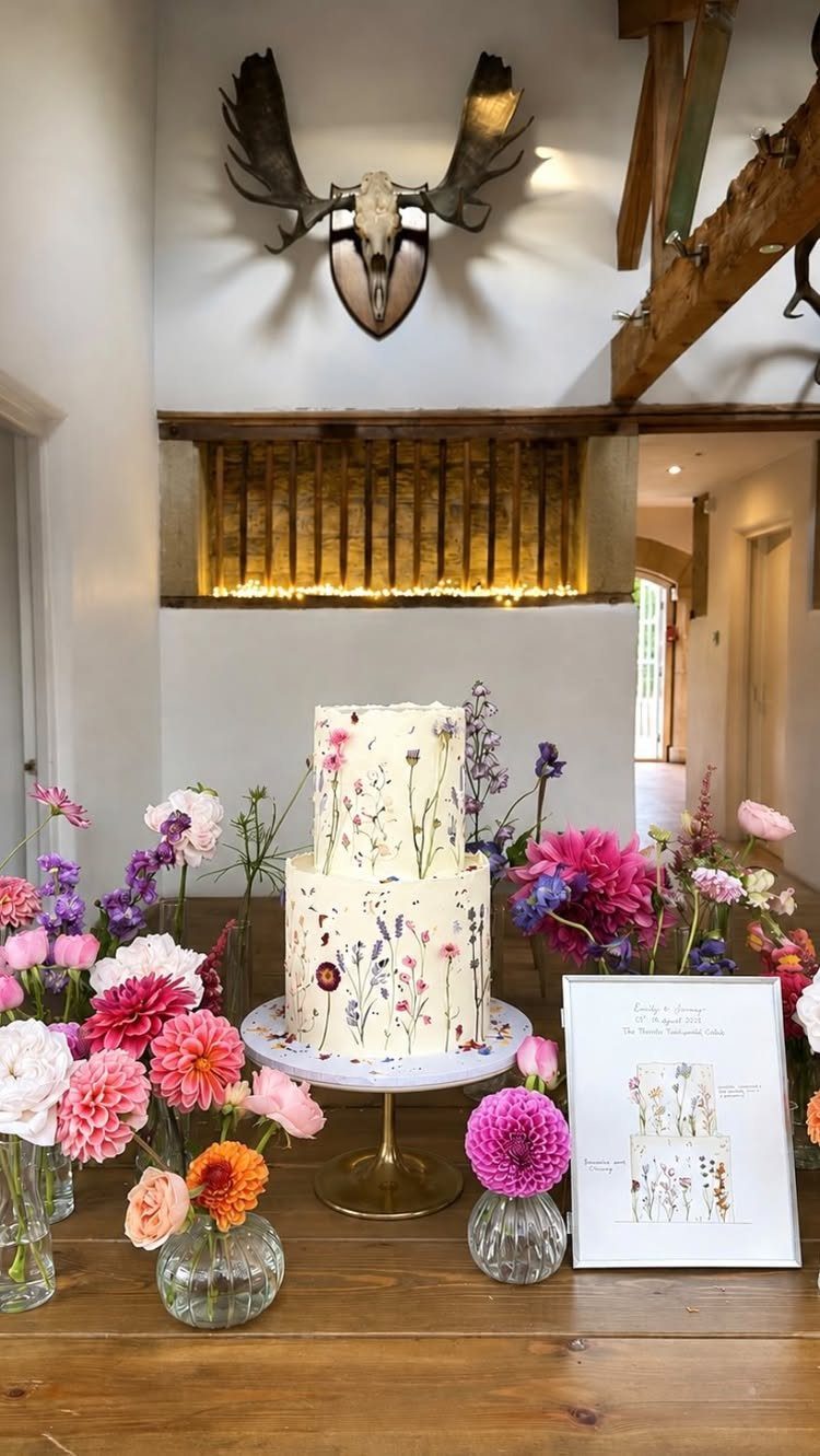 38 Romantic Wedding Cake Ideas for Your Celebration 5 Two-tier semi-naked cake decorated with pressed wildflowers on a gold cake stand.