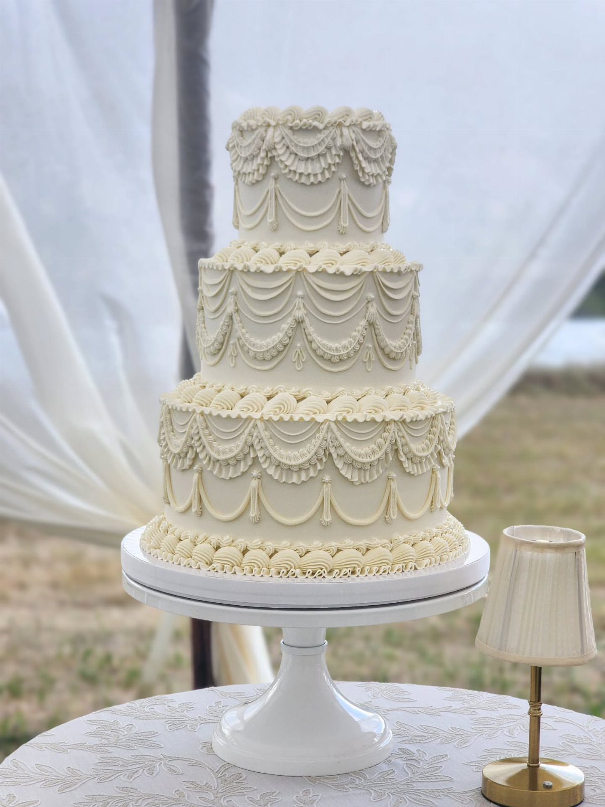 38 Romantic Wedding Cake Ideas for Your Celebration 3 Three-tier white wedding cake with ornate vintage buttercream piping on a white pedestal stand