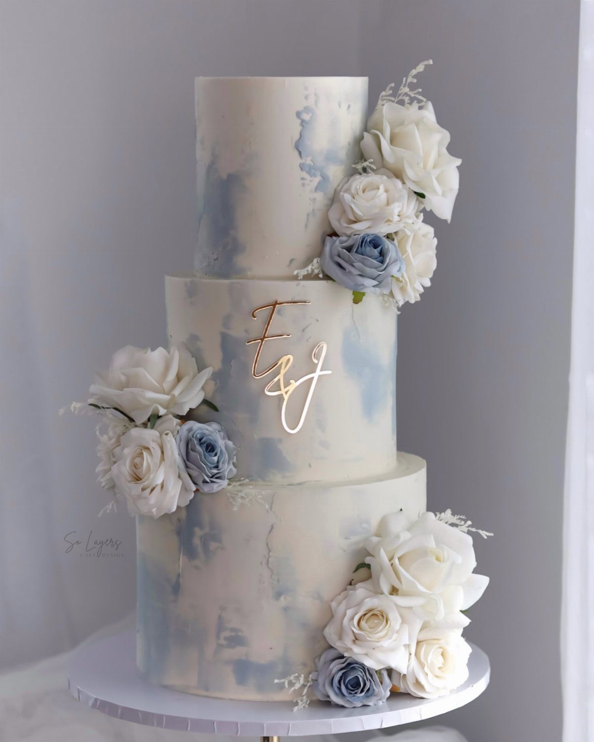 38 Romantic Wedding Cake Ideas for Your Celebration 11 Three-tier white wedding cake with blue watercolor painting and white and blue roses.