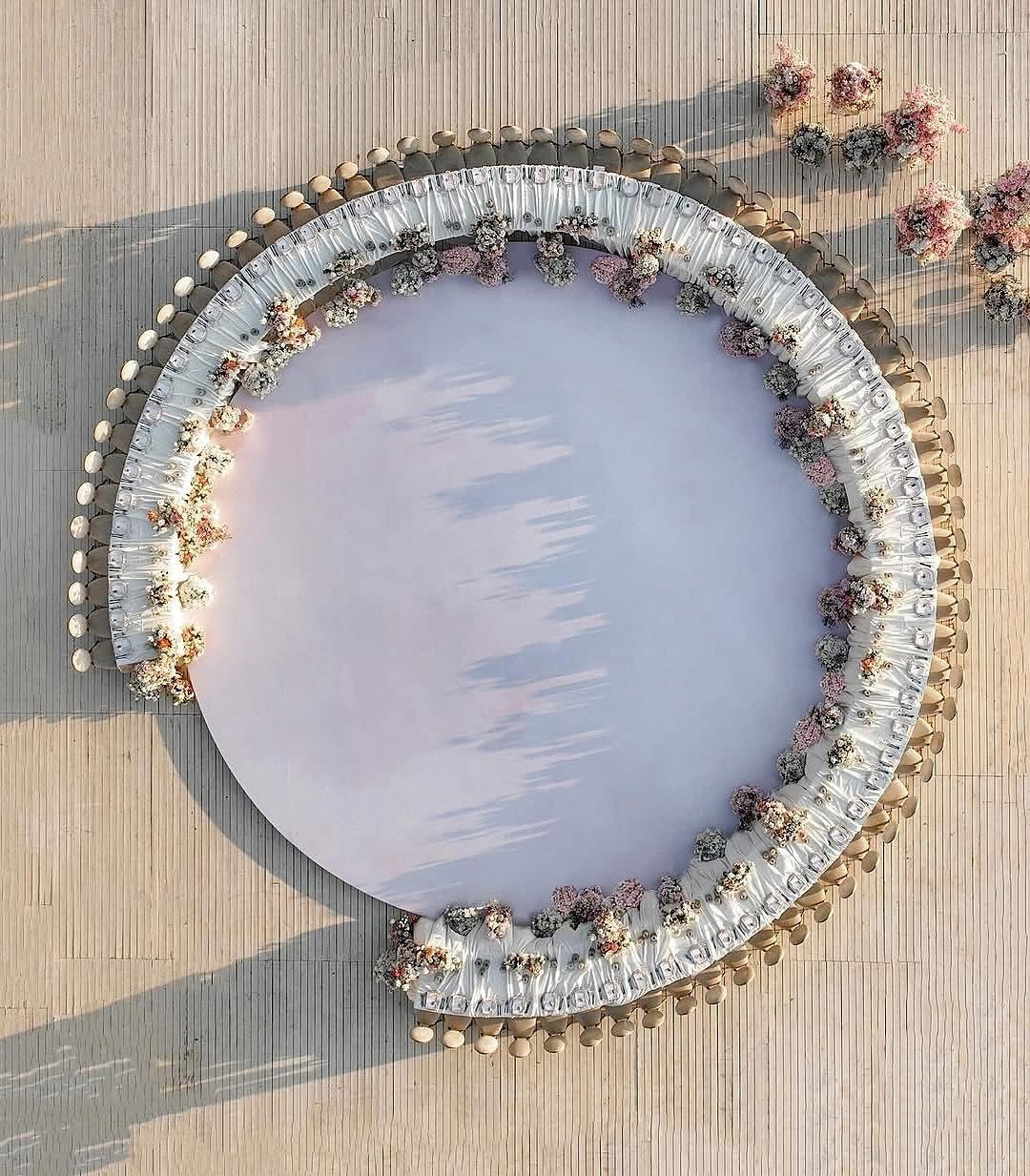 13 Round Table Wedding Decor Ideas: From S-Curved Layouts to Draped Florals 14 Aerial view of a large round wedding table with white linen and floral accents.