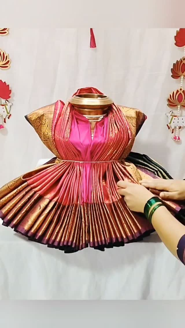 Pink and gold silk saree draped around a brass kalasam pot with gold belt.