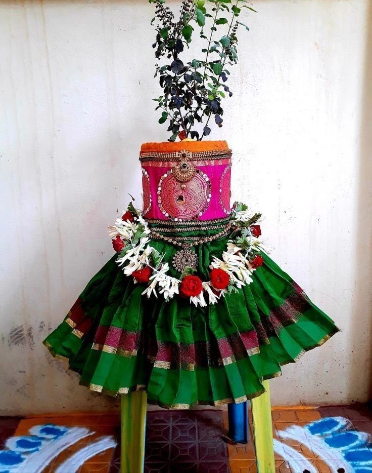 Saree wrapped pot with pink and green fabric, floral garland, and a plant.