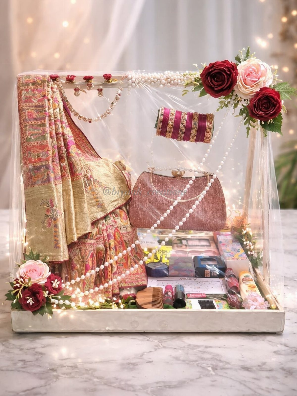 Saree and cosmetics gift set in a clear acrylic box with roses and lights.