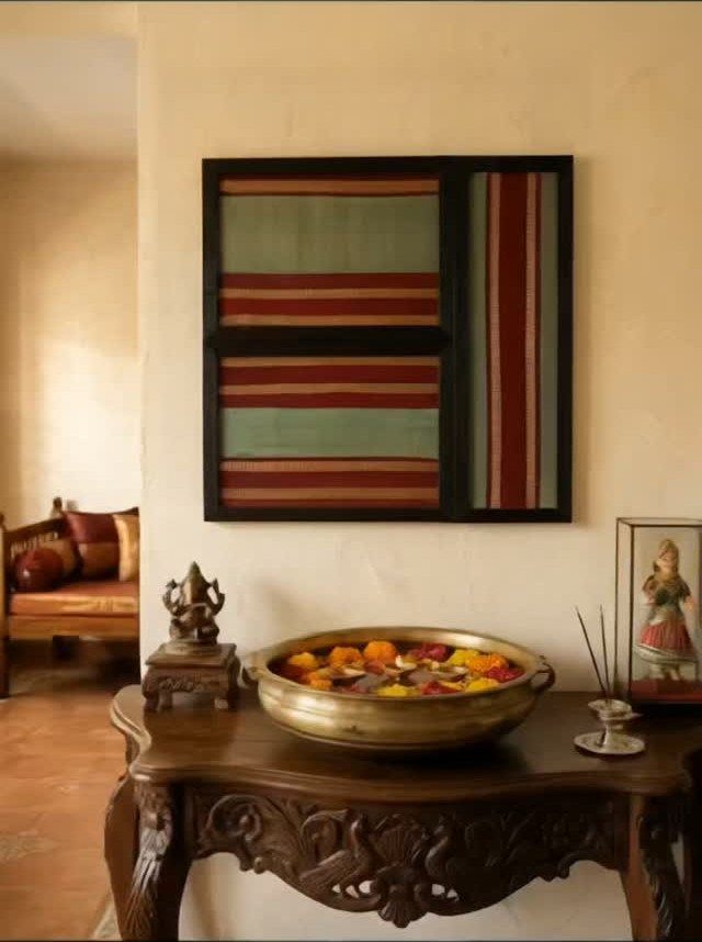 Framed striped silk saree fabric hanging on a wall above a wooden table.