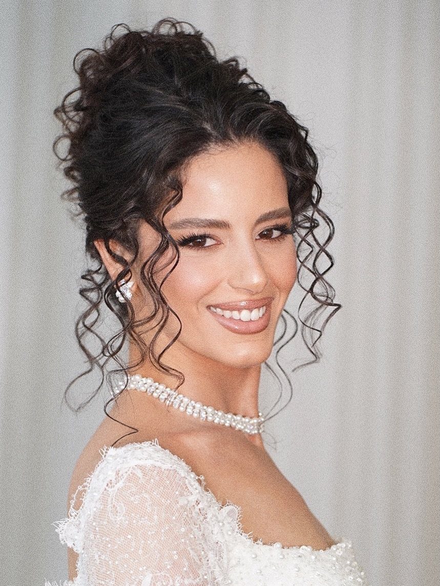 9 Short Curly Hairstyles for Wedding Day Perfection 10 Woman with curly dark hair updo wearing a white lace wedding dress and jewelry