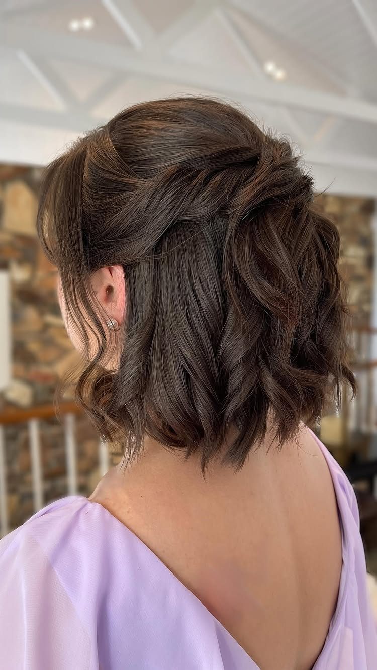 Woman with dark brown wavy bob hair styled in a romantic half-up wedding look.