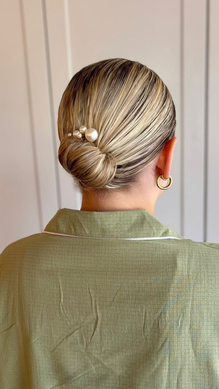 Blonde hair styled in a sleek low bun decorated with a pearl hair clip.