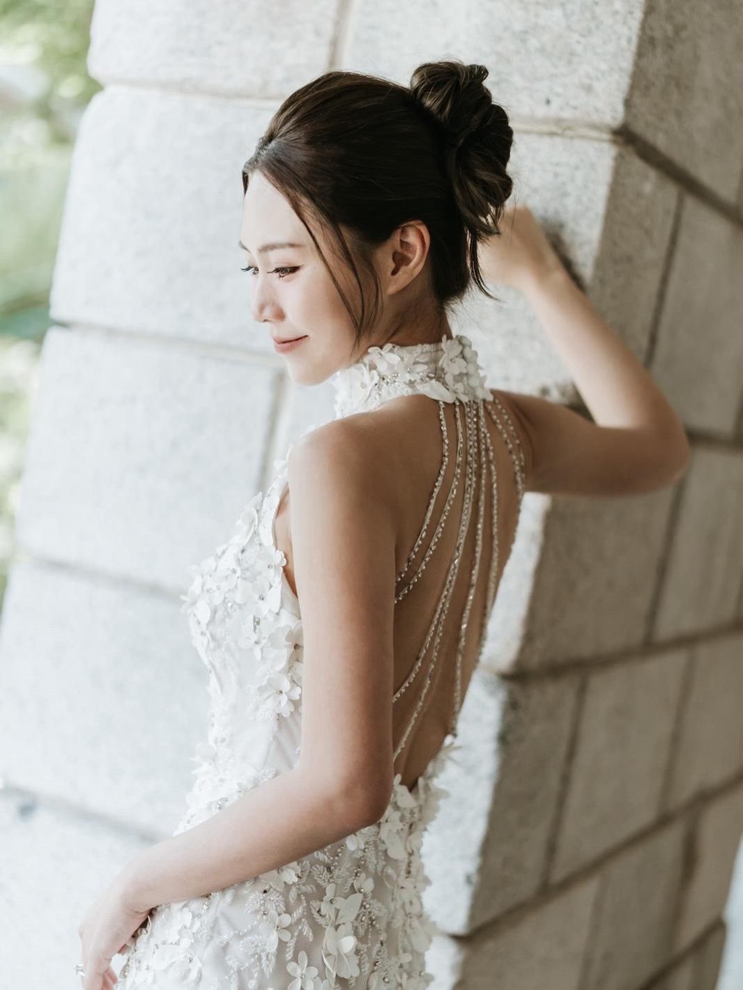 Woman in a white floral wedding dress with a pearl-draped open back.