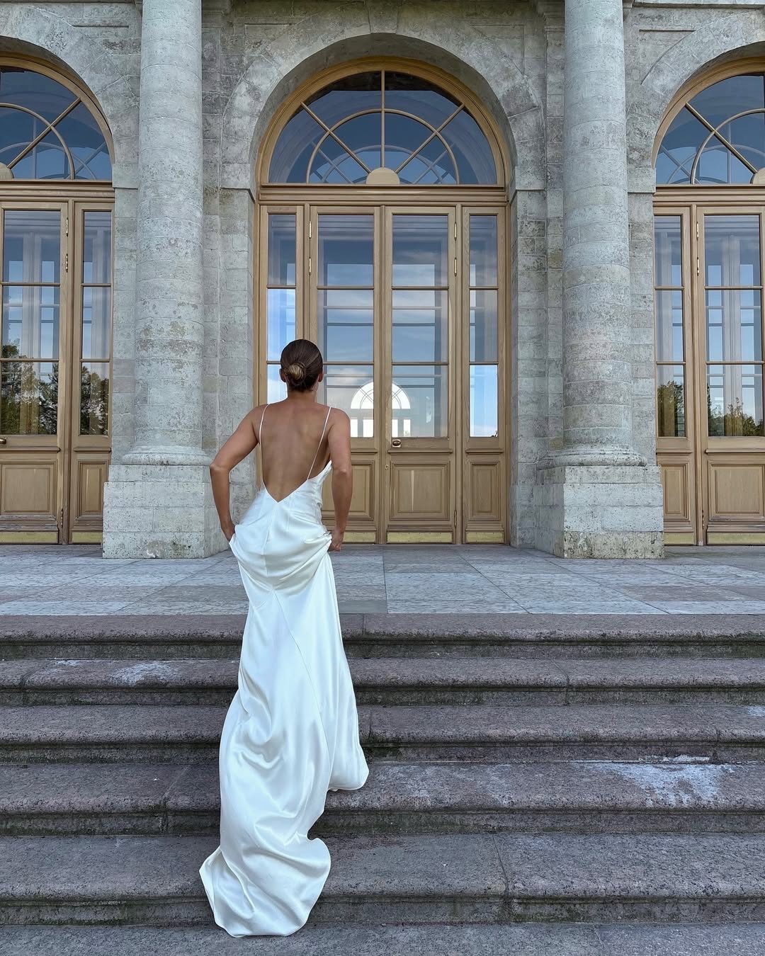 Woman in white silk wedding dress with low scoop back on stone steps
