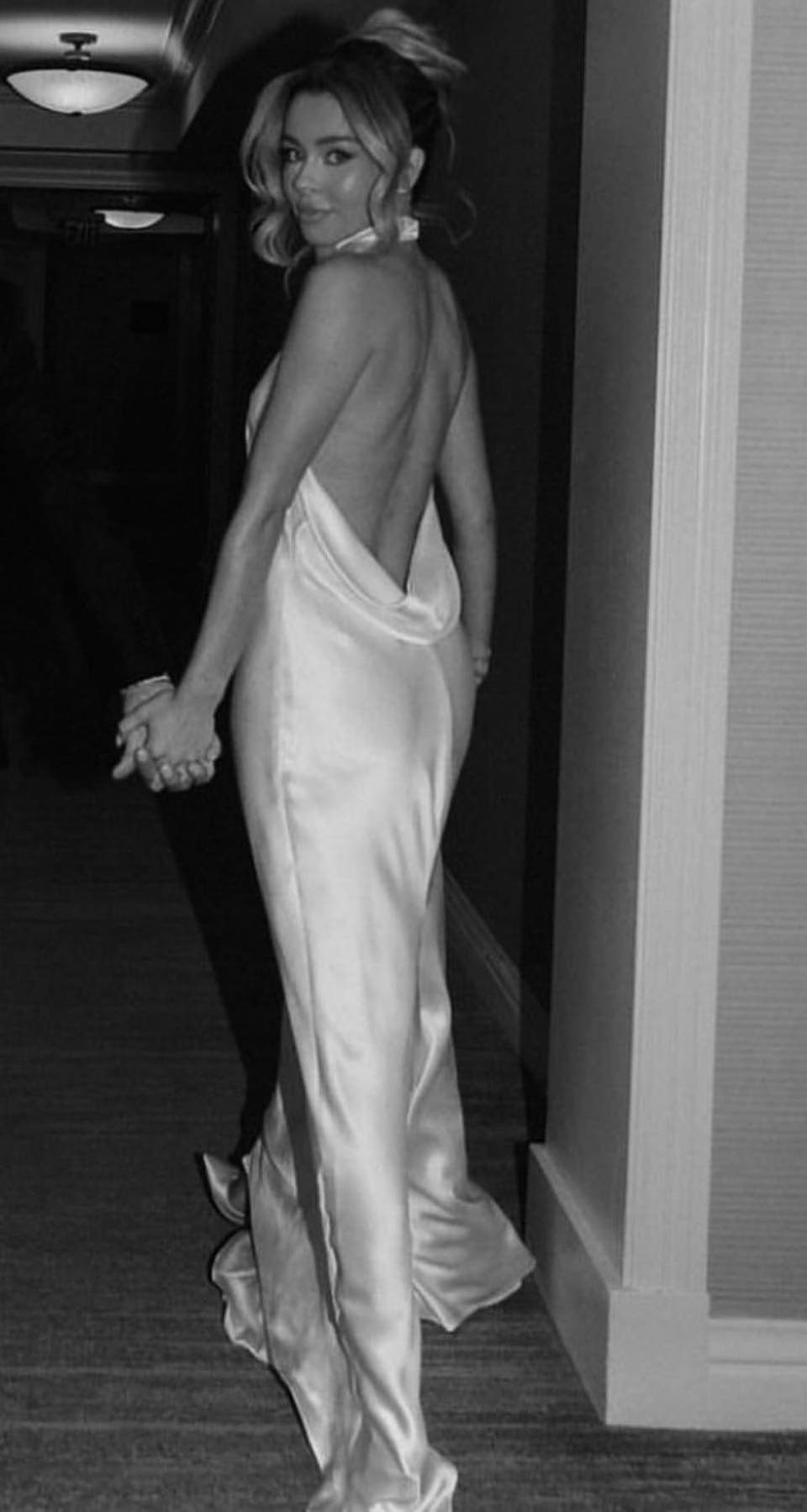 Woman in a shimmering silk backless gown with a deep cowl back.