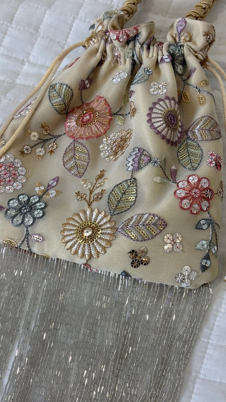 Sister Wedding Gift Ideas: 34 Picks She'll Treasure 34 Embroidered floral drawstring pouch with silver fringe on a white quilted background.