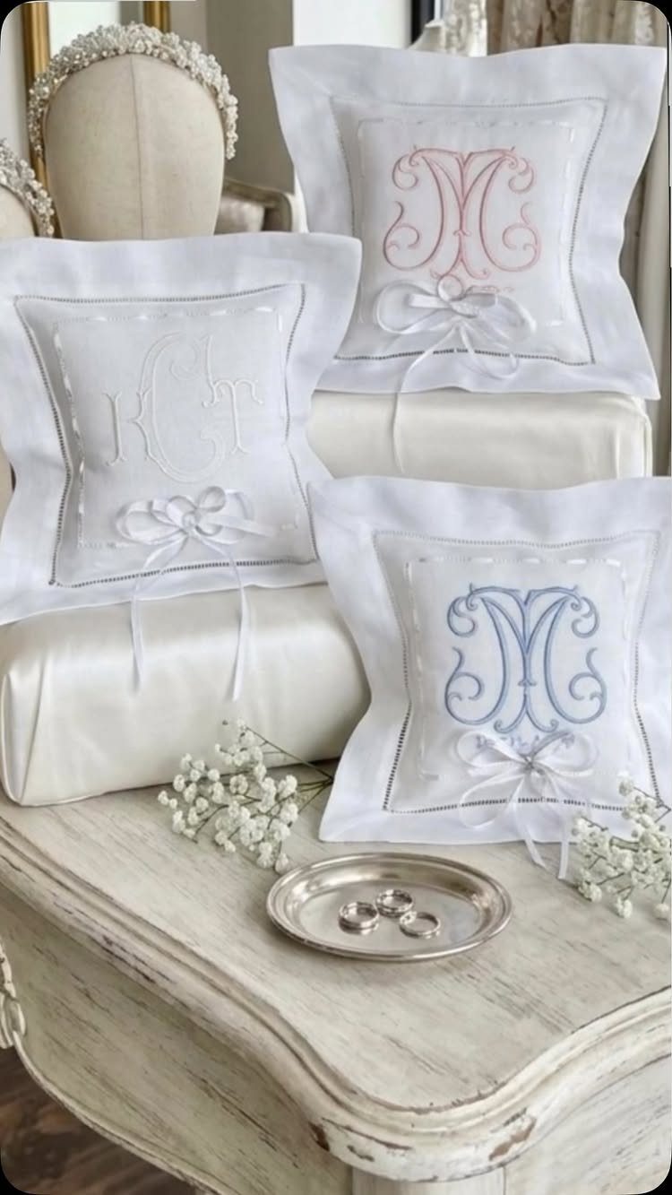 Sister Wedding Gift Ideas: 34 Picks She'll Treasure 32 White satin wedding ring pillows with monograms on a vintage white wooden table.