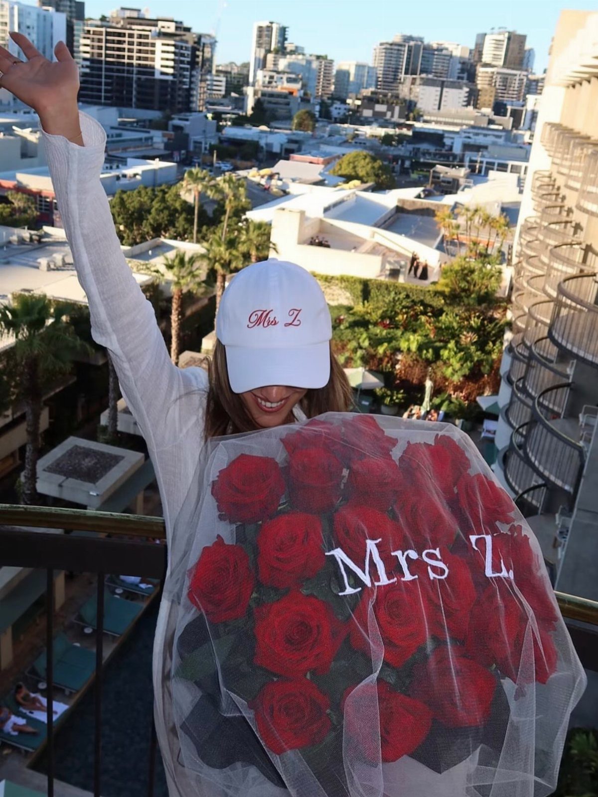 Sister Wedding Gift Ideas: 34 Picks She'll Treasure 14 Woman wearing a white Mrs Z baseball cap holding a large red rose bouquet.