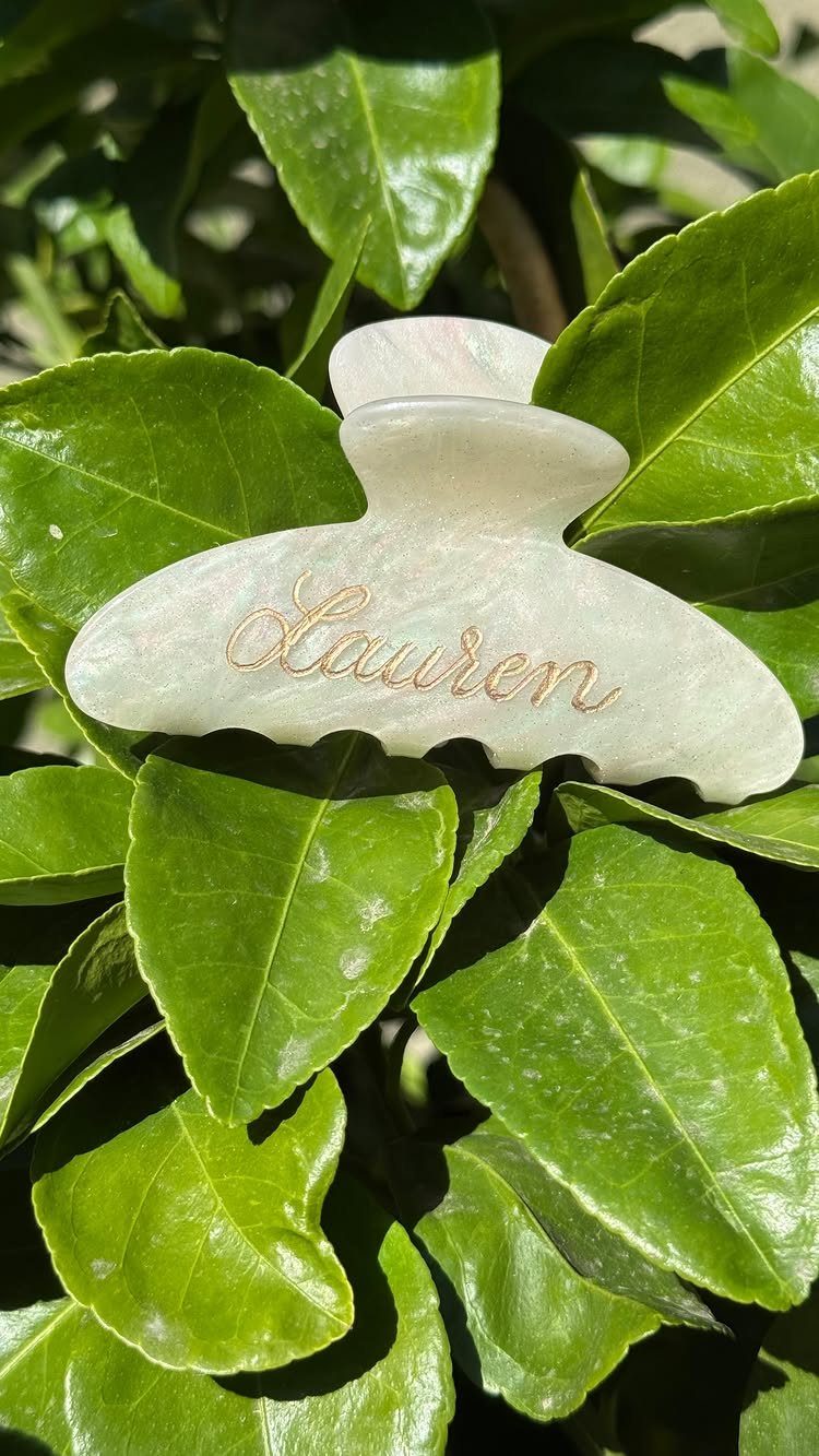 Sister Wedding Gift Ideas: 34 Picks She'll Treasure 33 White pearlescent hair claw clip with gold cursive name Lauren on green leaves