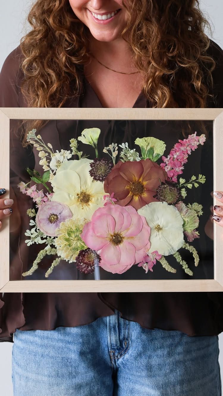 Sister Wedding Gift Ideas: 34 Picks She'll Treasure 31 Pressed dried flower arrangement in a wooden frame held by a woman.