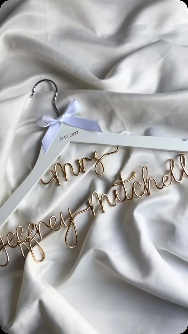 Sister Wedding Gift Ideas: 34 Picks She'll Treasure 24 White wooden wedding dress hanger with gold wire script and white satin backdrop