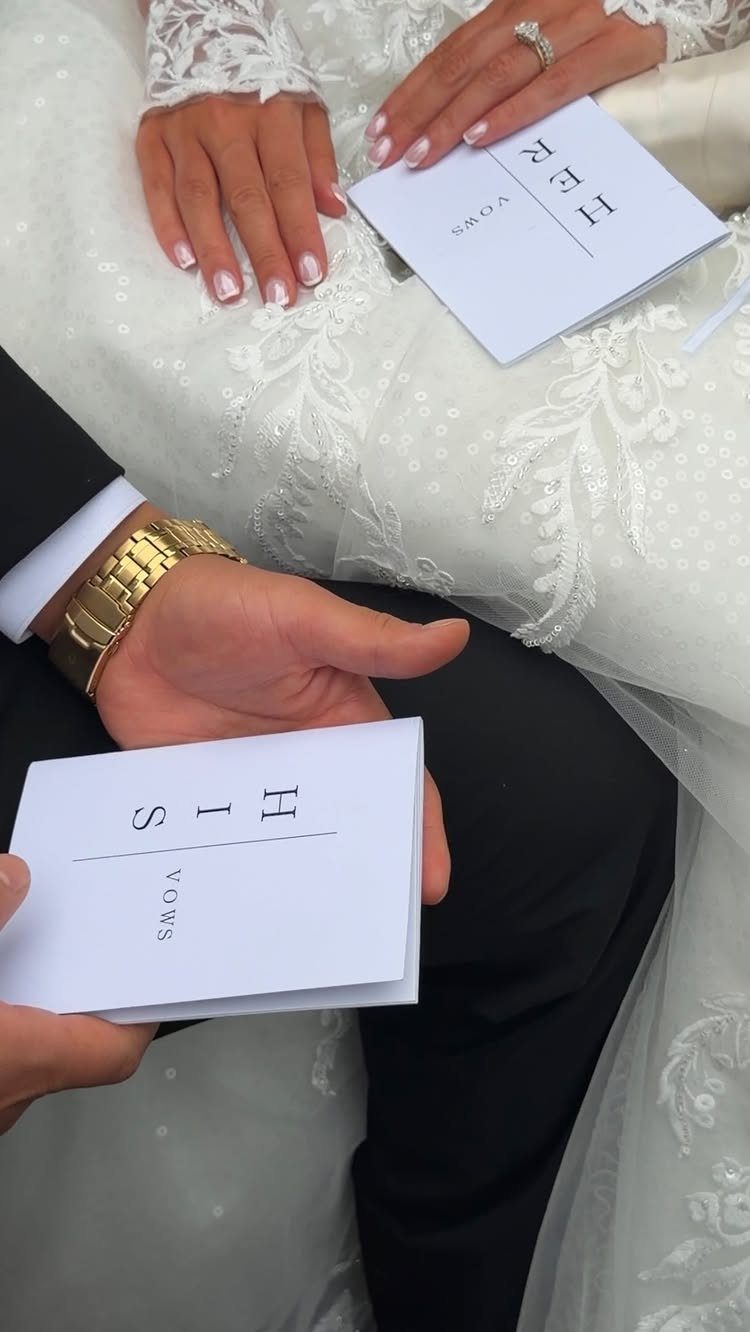Bride and groom holding white vow booklets during a wedding ceremony.