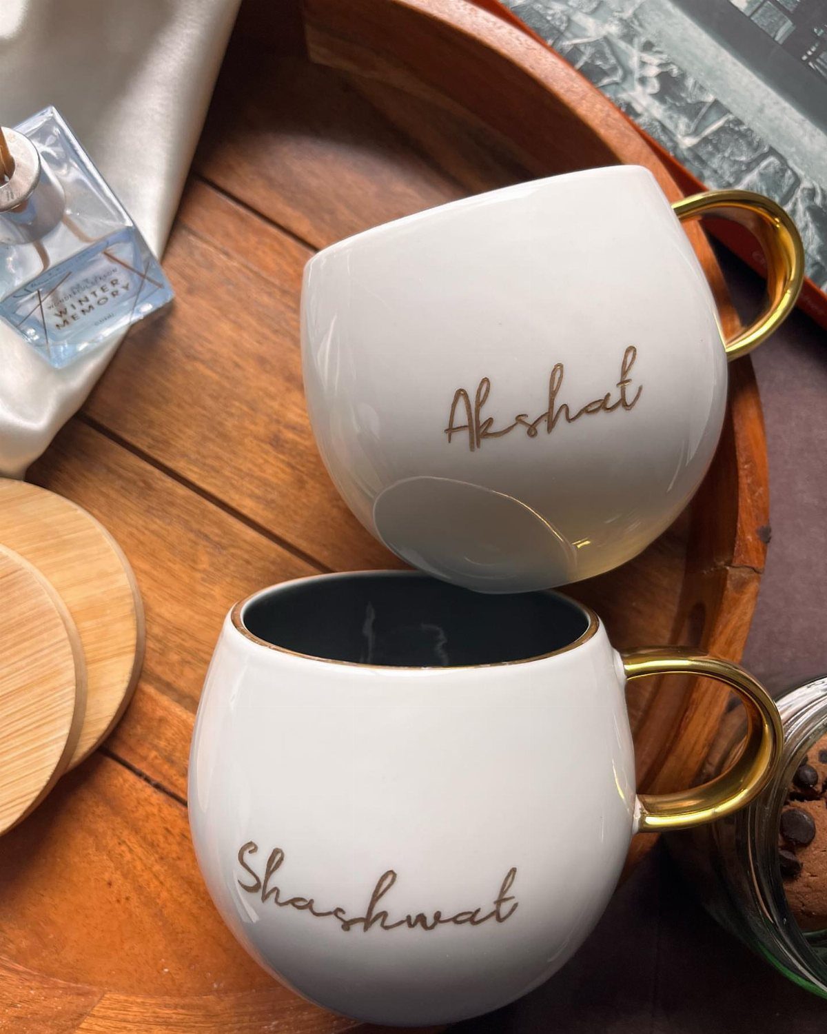 20 Small Wedding Gift Ideas for Couples Who Have Everything 8 Two white ceramic mugs with gold handles and personalized names in brown cursive script.