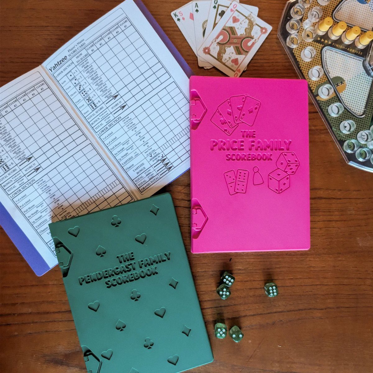 20 Small Wedding Gift Ideas for Couples Who Have Everything 17 Two personalized family game night scorebooks with playing cards and dice on wood.