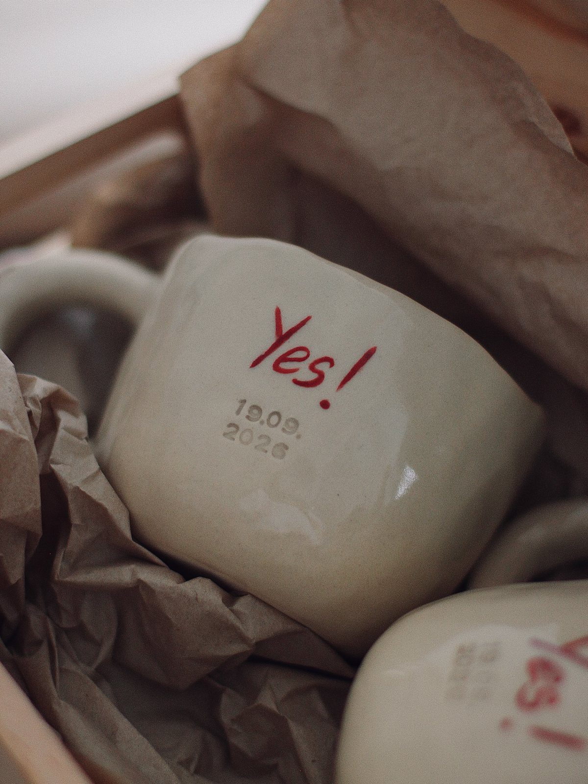 20 Small Wedding Gift Ideas for Couples Who Have Everything 21 Beige ceramic mug with red Yes! text and a date in packing paper.