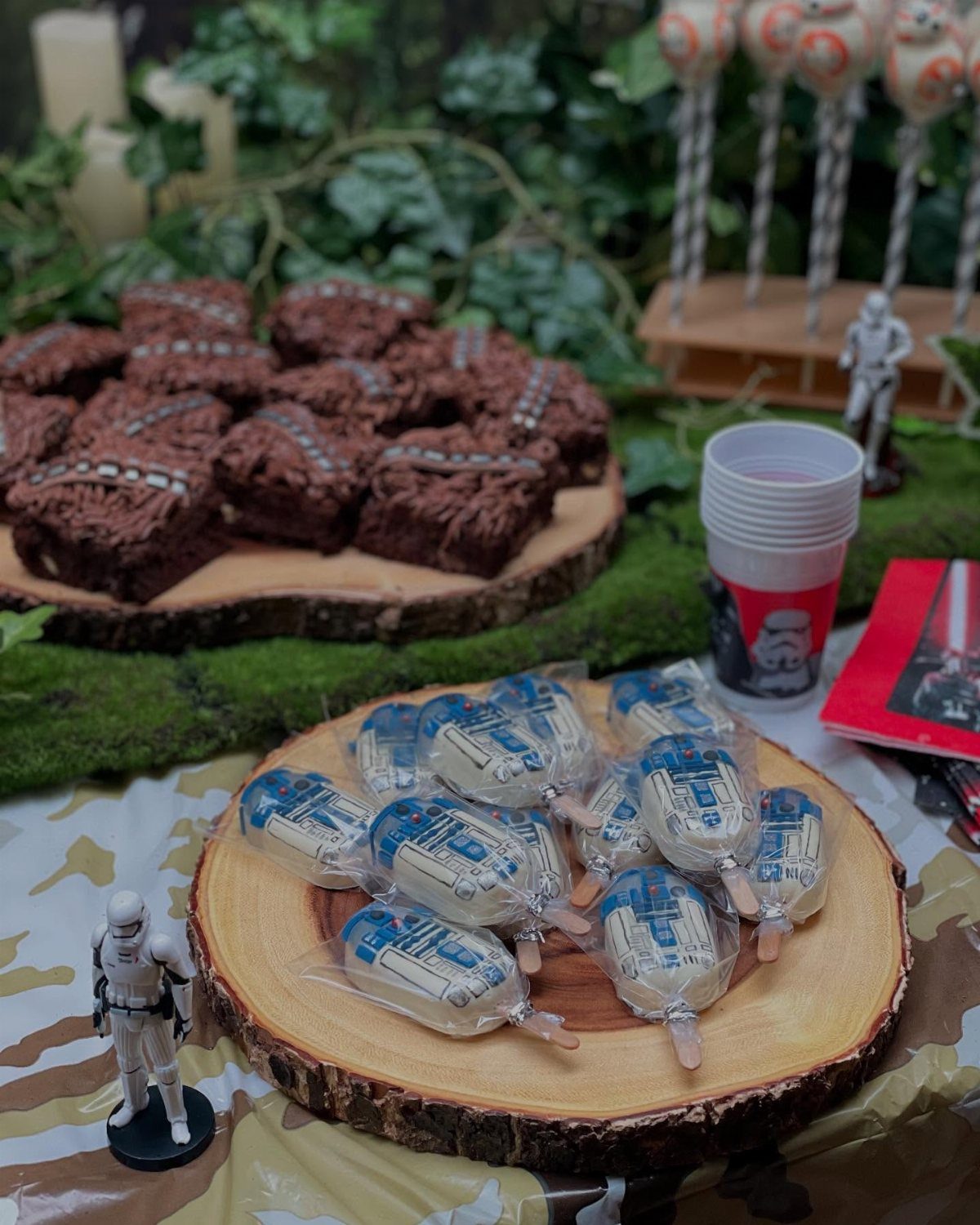 Star Wars themed dessert table with brownies, treats, and Stormtrooper figurines on wood slabs.