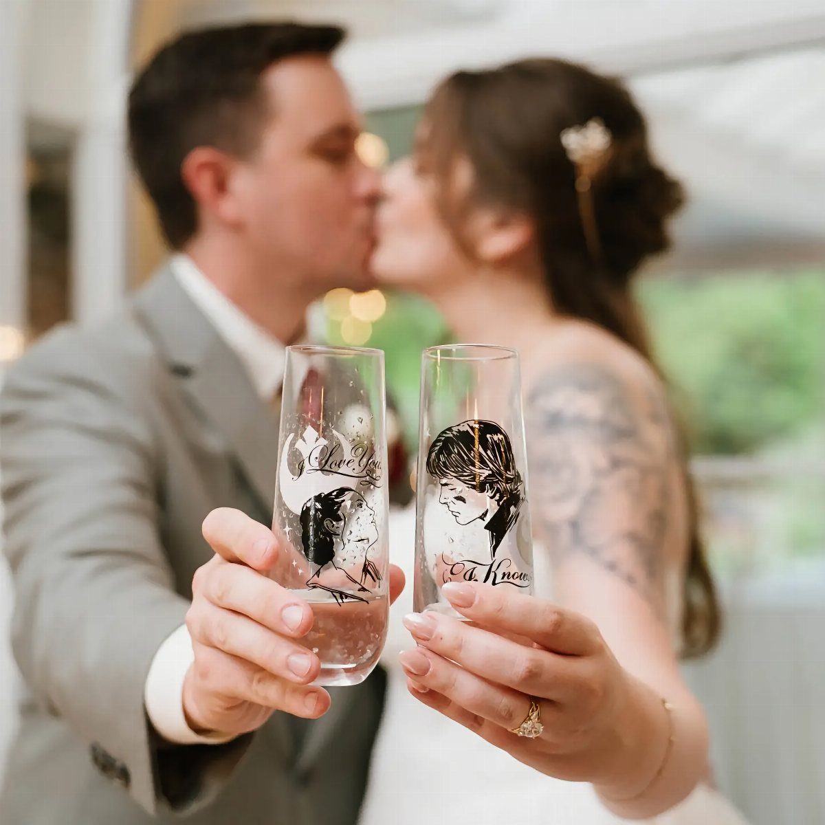 Champagne flutes with Han and Leia illustrations held by a kissing wedding couple.