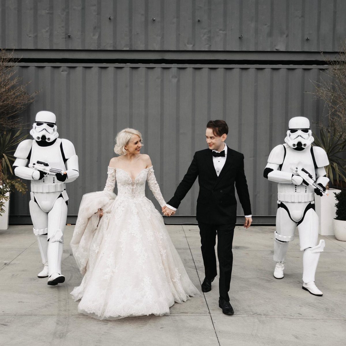 Bride and groom walking between two Stormtroopers in full armor at a wedding.