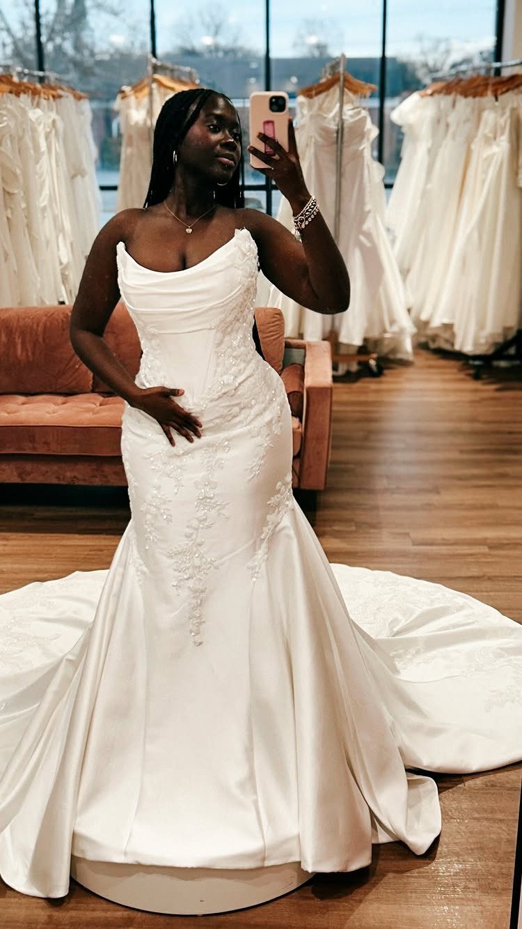Vintage Elegant Wedding Dress Ideas in 12 Styles 11 Woman in a white fit-and-flare wedding gown posing in a bridal boutique mirror selfie.