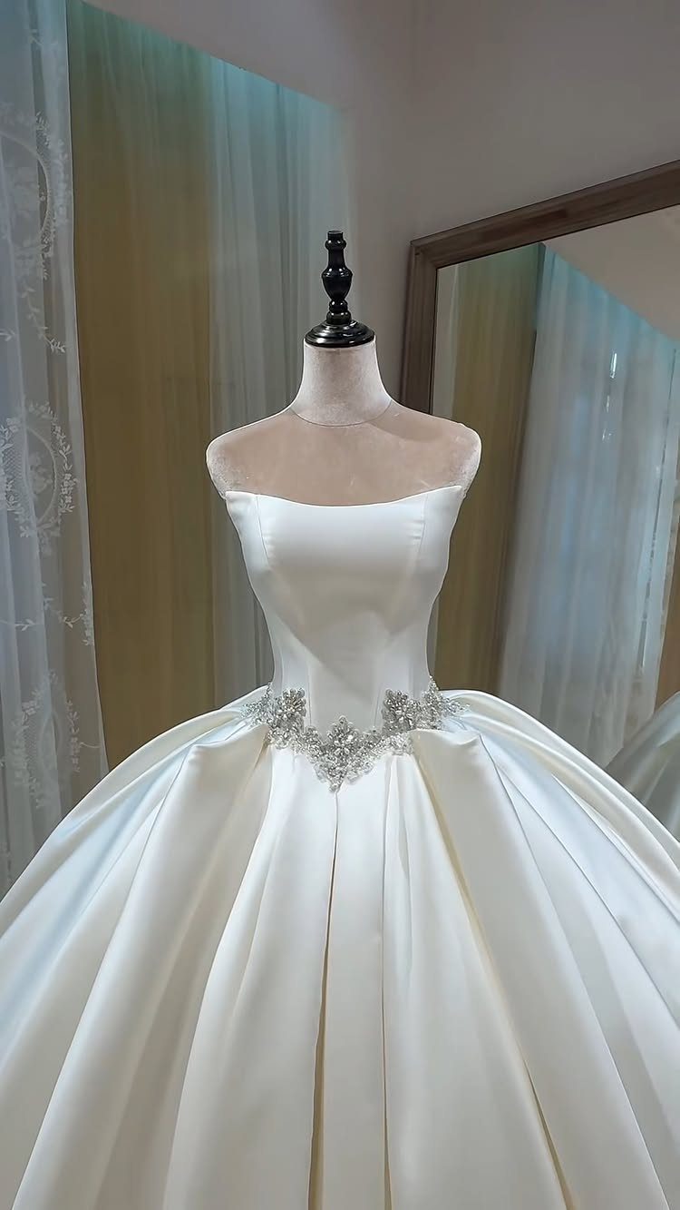 Vintage Elegant Wedding Dress Ideas in 12 Styles 12 White satin strapless ballgown wedding dress with a sparkling crystal belt on a mannequin