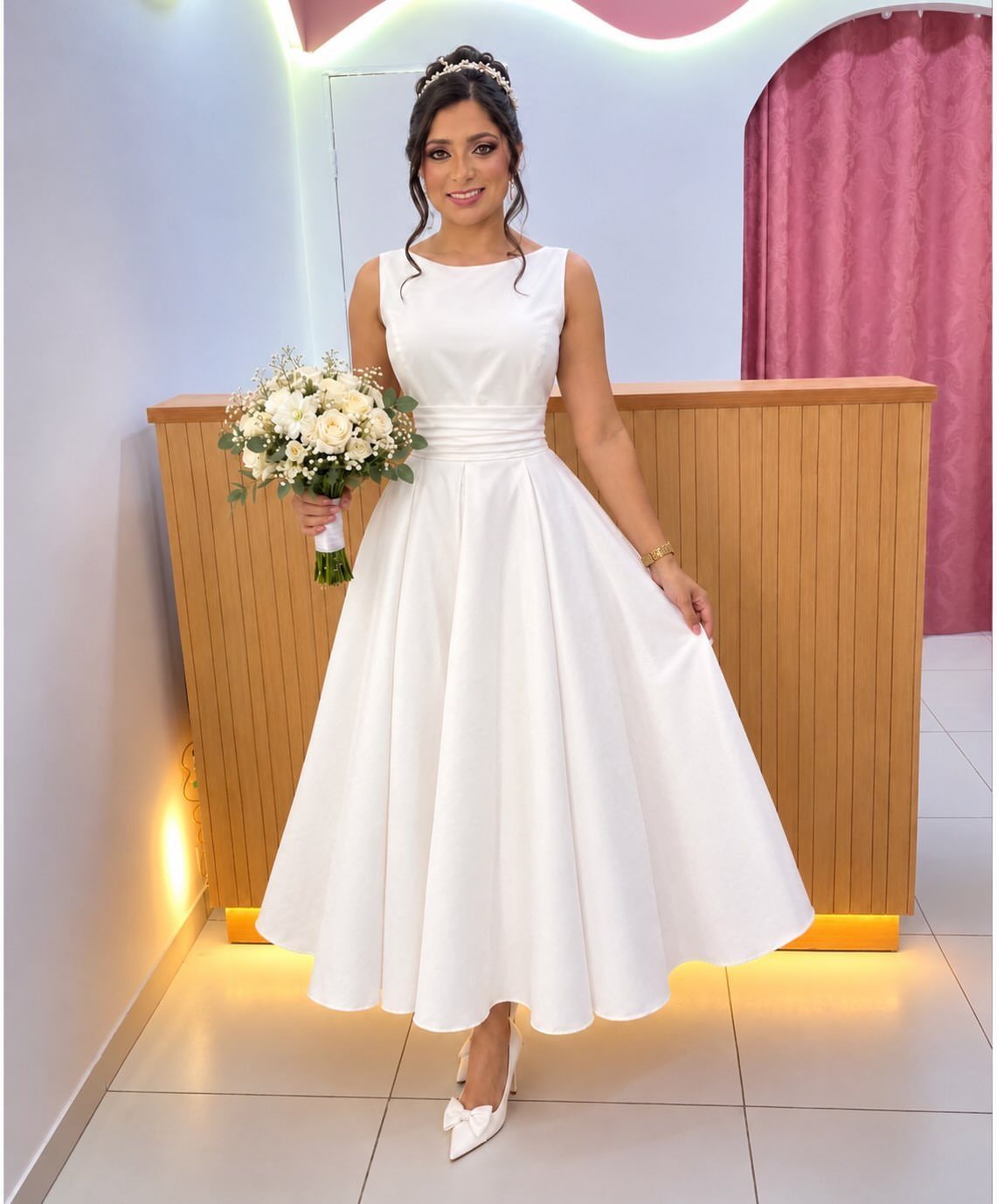 Vintage Elegant Wedding Dress Ideas in 12 Styles 8 Woman in a tea-length white satin wedding dress holding a white floral bouquet.