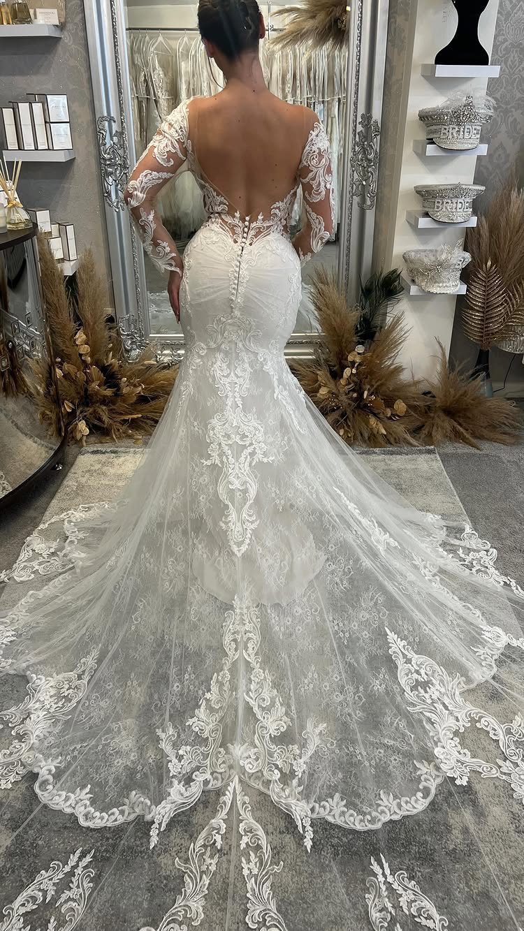 Vintage Elegant Wedding Dress Ideas in 12 Styles 3 Woman wearing a white lace wedding gown with a long train in a boutique.