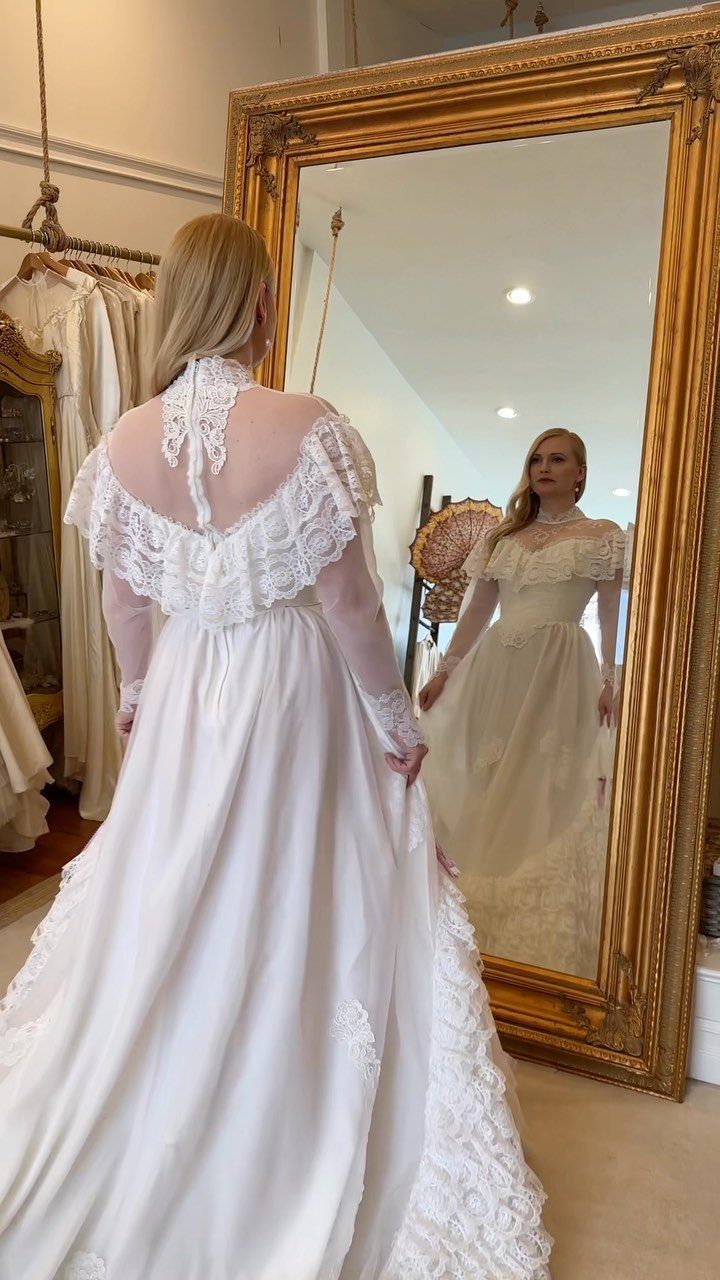 Vintage Elegant Wedding Dress Ideas in 12 Styles 5 Woman wearing a white vintage wedding gown with lace, reflected in a gold mirror.