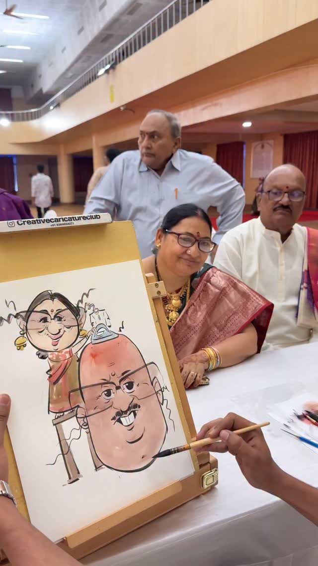 19 Wedding Activities for Guests: Reception Ideas Fun Enough to Fill the Whole Night 13 Caricature artist drawing a funny portrait of a seated couple on a white easel.