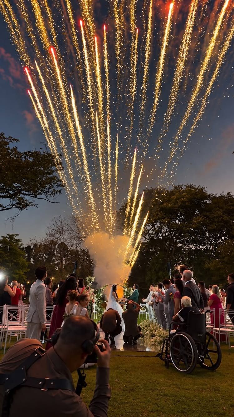 19 Wedding Activities for Guests: Reception Ideas Fun Enough to Fill the Whole Night 5 Golden fireworks erupting into the twilight sky above a crowd of wedding guests outdoors.