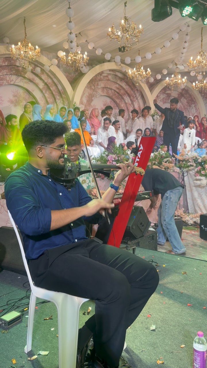 19 Wedding Activities for Guests: Reception Ideas Fun Enough to Fill the Whole Night 12 A man playing the violin while seated in front of a large crowd at an event.