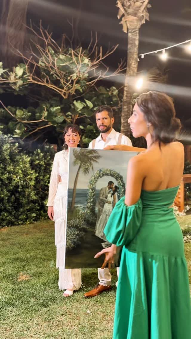 19 Wedding Activities for Guests: Reception Ideas Fun Enough to Fill the Whole Night 3 A woman in a green dress displays a large canvas painting of a wedding couple outdoors.