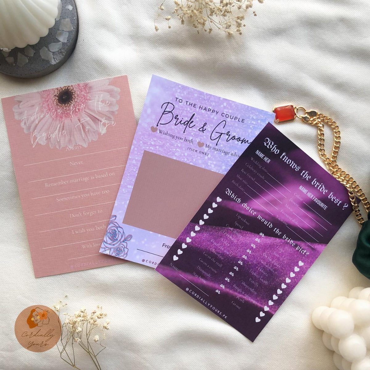 19 Wedding Activities for Guests: Reception Ideas Fun Enough to Fill the Whole Night 16 Three colorful wedding stationery cards with floral and celestial designs resting on a white fabric surface.