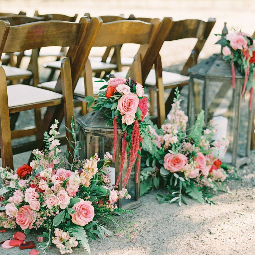 35 Backyard Wedding Reception Ideas for an Unforgettable Day 13 Wooden wedding chairs with a sandy aisle lined by lanterns and pink floral arrangements.