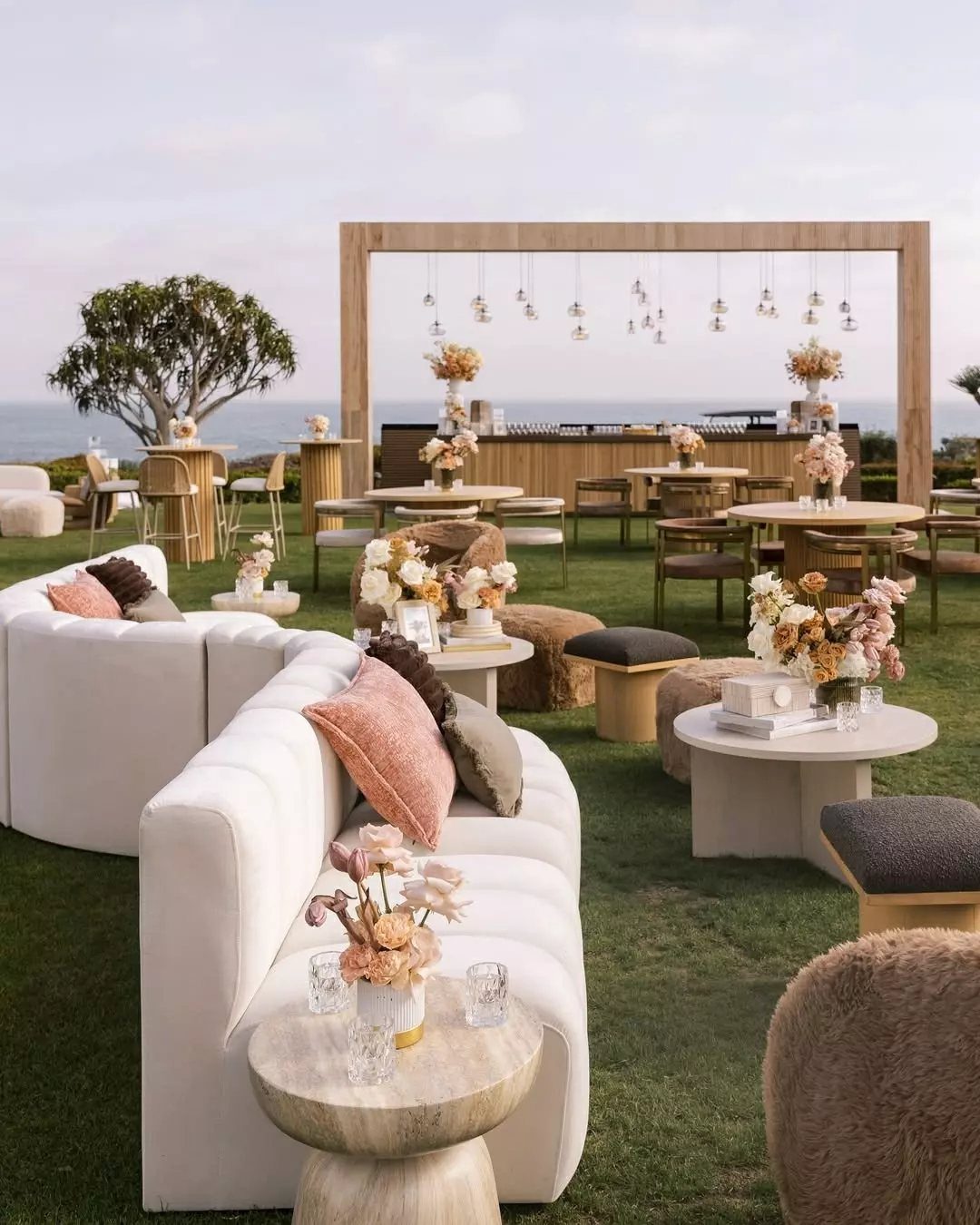 35 Backyard Wedding Reception Ideas for an Unforgettable Day 8 Outdoor lounge area with white curved sofas and small tables on a green lawn.