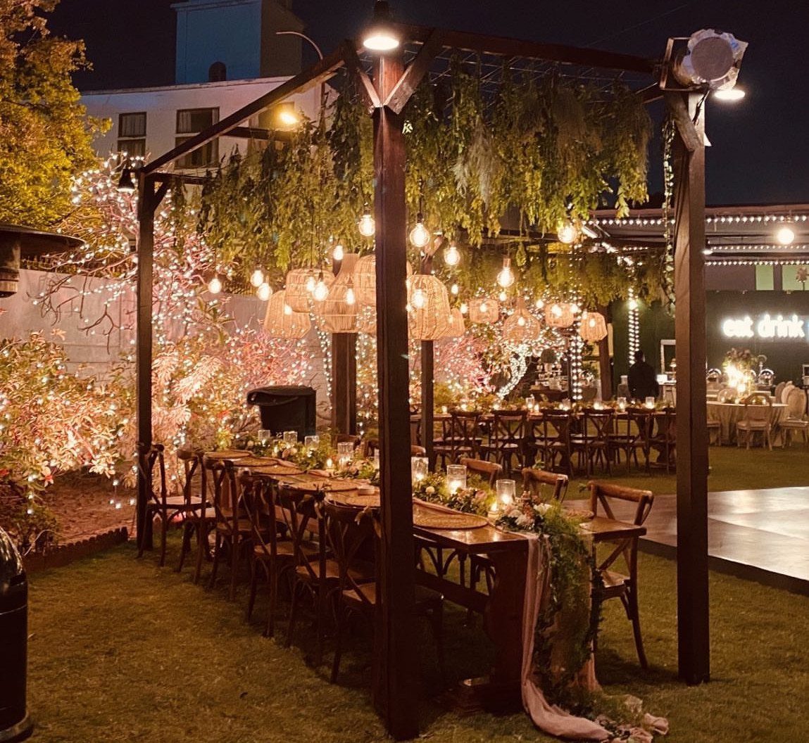 35 Backyard Wedding Reception Ideas for an Unforgettable Day 12 Woven rattan chandeliers hanging from a wooden pergola over a wedding dining table.