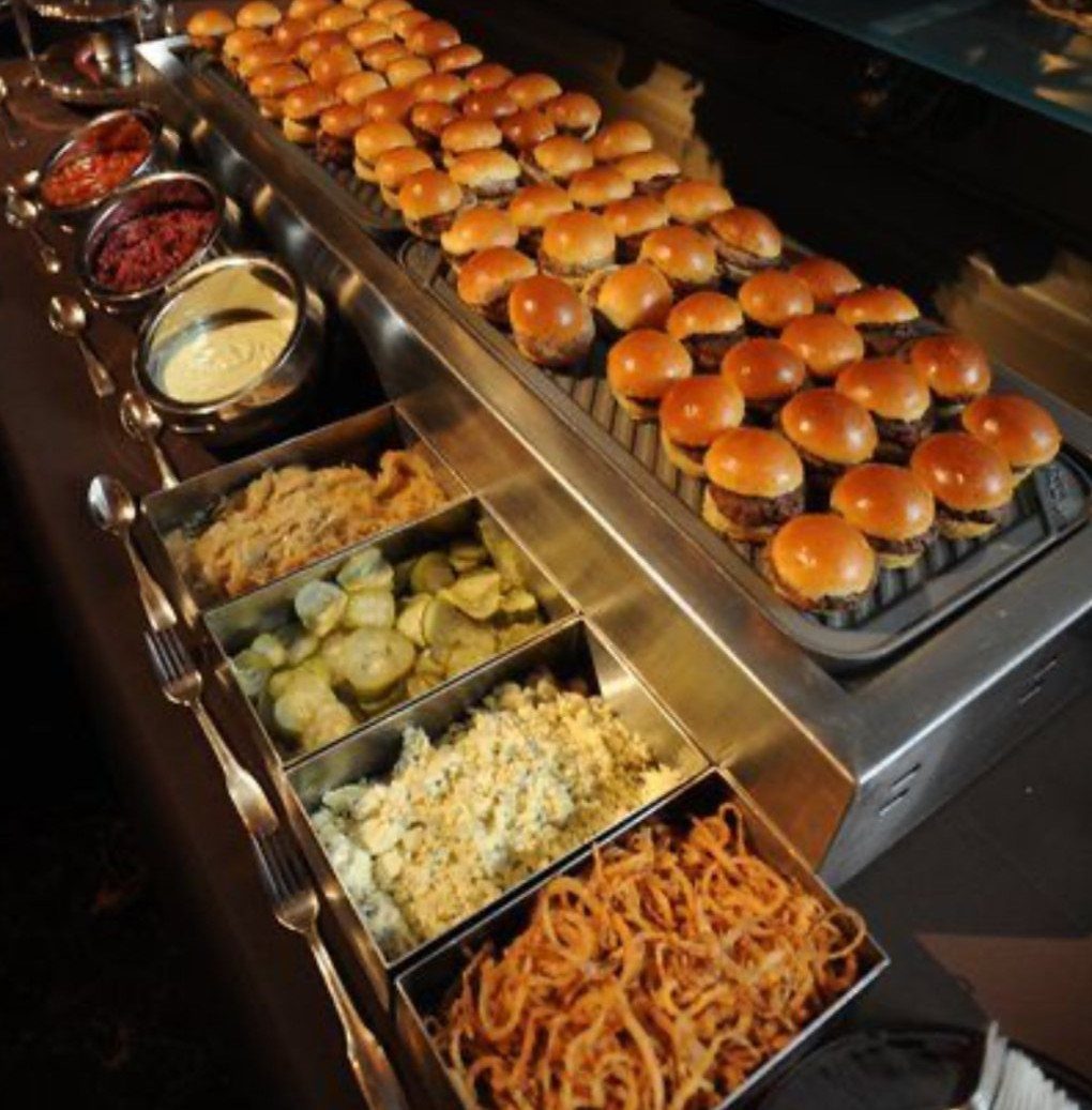 35 Backyard Wedding Reception Ideas for an Unforgettable Day 30 Rows of mini sliders and various side dishes served on a catering station.