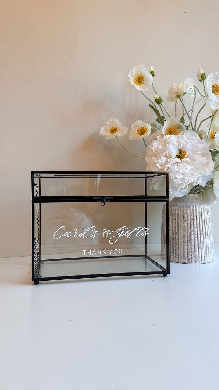 35 Backyard Wedding Reception Ideas for an Unforgettable Day 36 Glass card box with white lettering next to a vase of white flowers.