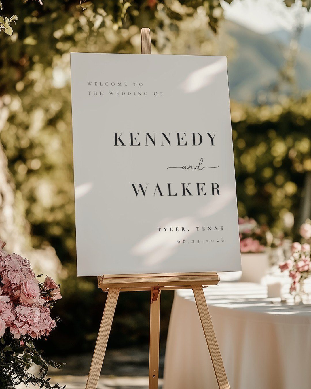 35 Backyard Wedding Reception Ideas for an Unforgettable Day 6 Wedding welcome sign on a wooden easel surrounded by greenery and pink flowers.