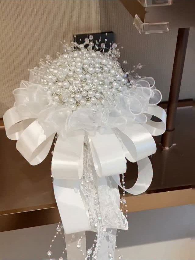 12 Wedding Bouquet Alternatives for Your Big Day 3 Pearl and crystal brooch bouquet with a large white satin bow and beads.