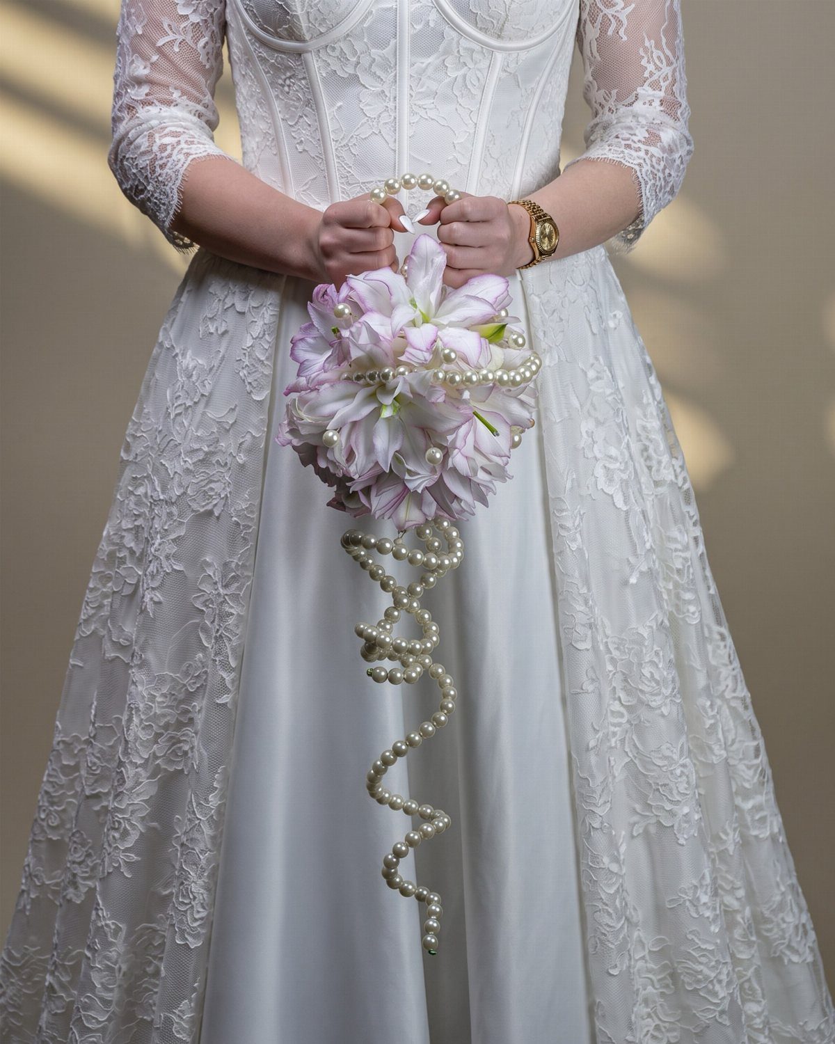 12 Wedding Bouquet Alternatives for Your Big Day 11 Pink and white lily bouquet wrapped in spiraling pearls held by a bride.