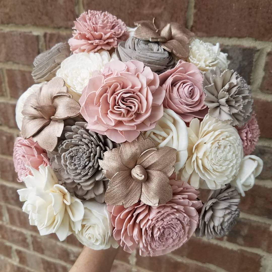 12 Wedding Bouquet Alternatives for Your Big Day 2 Sola wood flower bouquet in pink, cream, and gold held against brick wall.